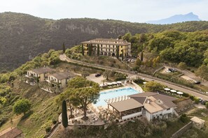 A large hotel with multiple buildings, a swimming pool, and a scenic mountainous backdrop. - Residence San Michele (Costermano sul Garda)