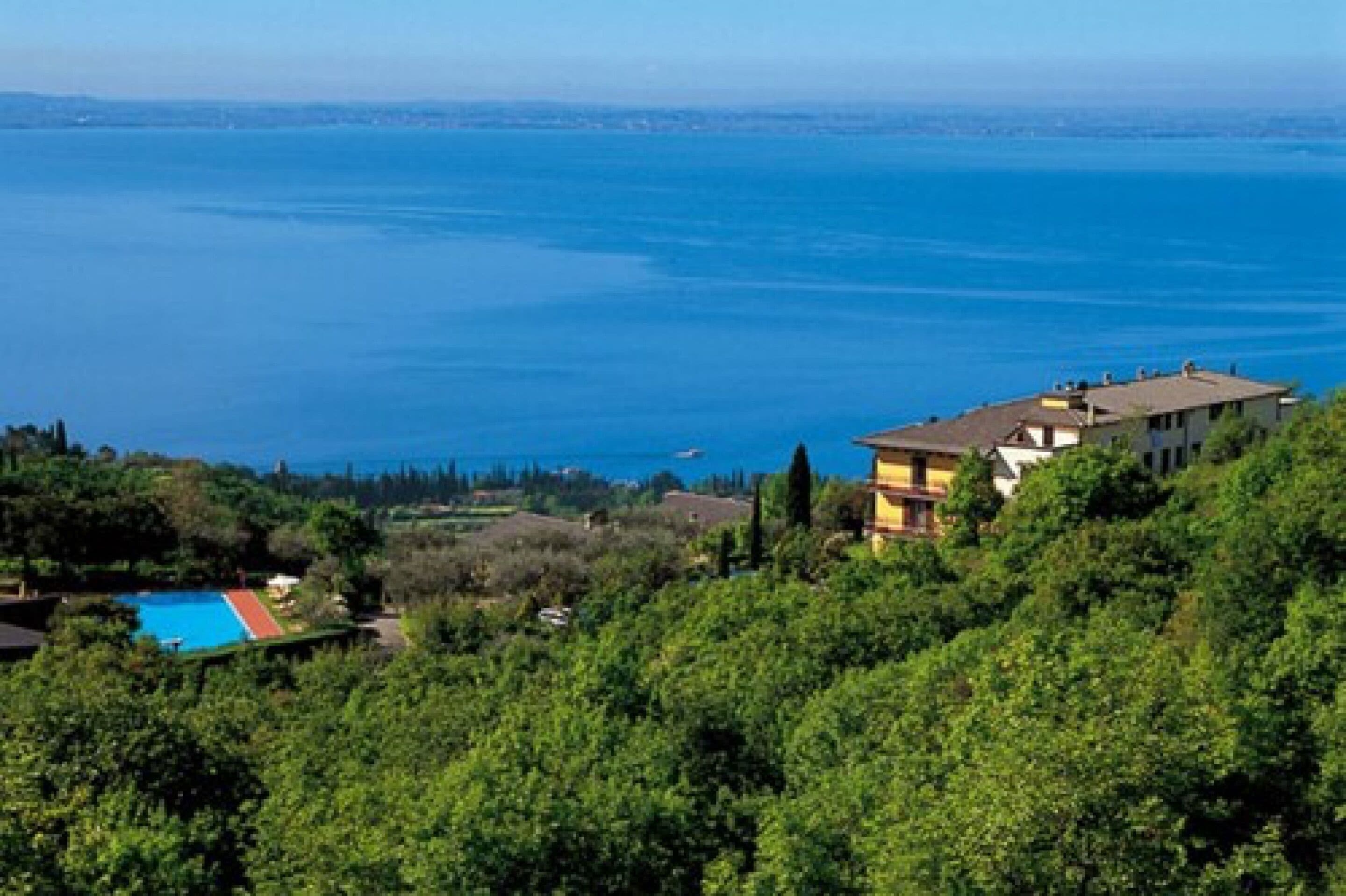 Une propriété située sur la côte, dotée d’une piscine, offrant une vue sur la mer et s’étendant sur une colline boisée.