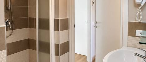 A bathroom with a shower, a sink, and a hairdryer on the wall.