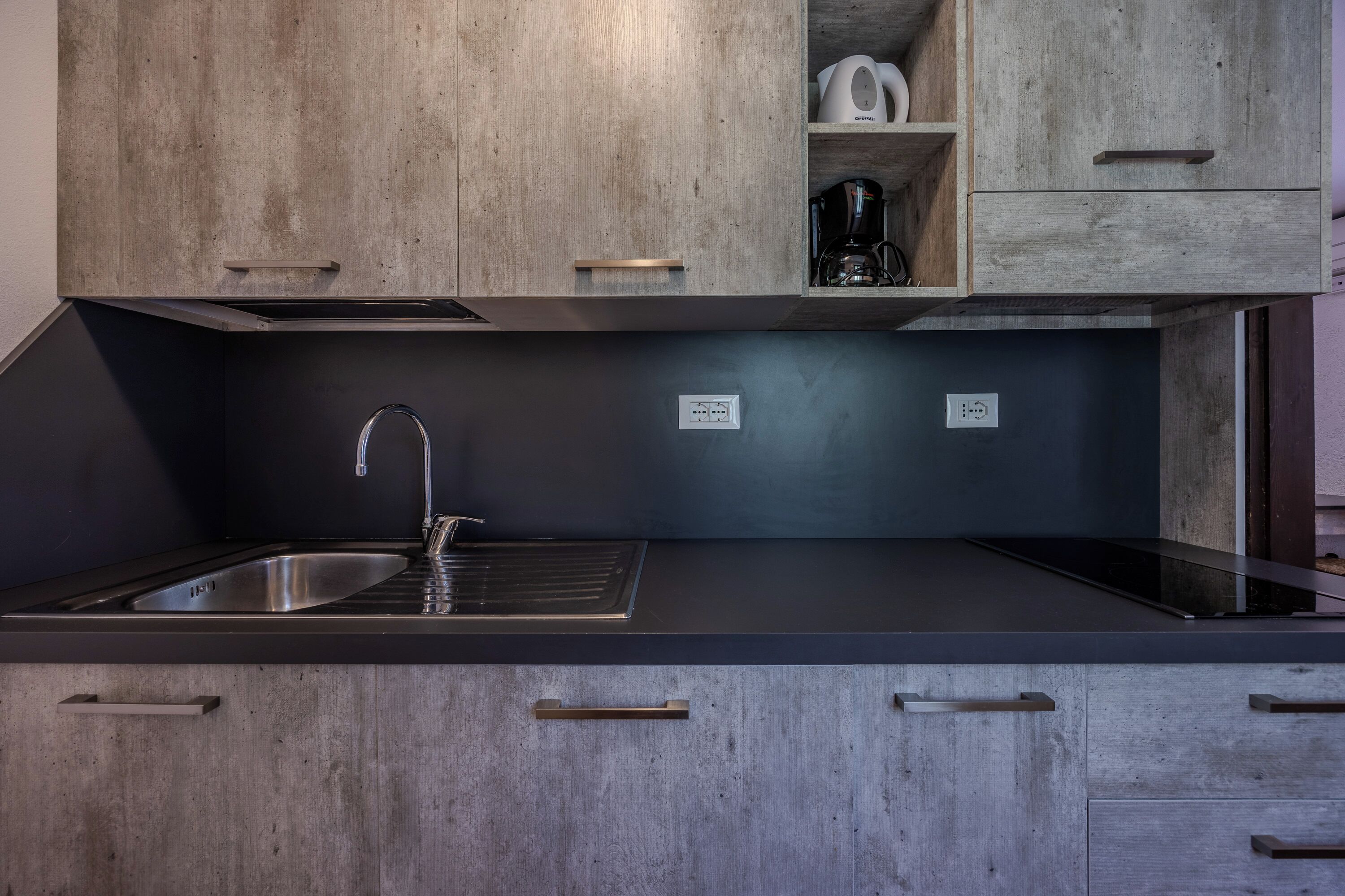 A modern kitchen with wooden cabinets, a stainless steel sink, and a black countertop.
