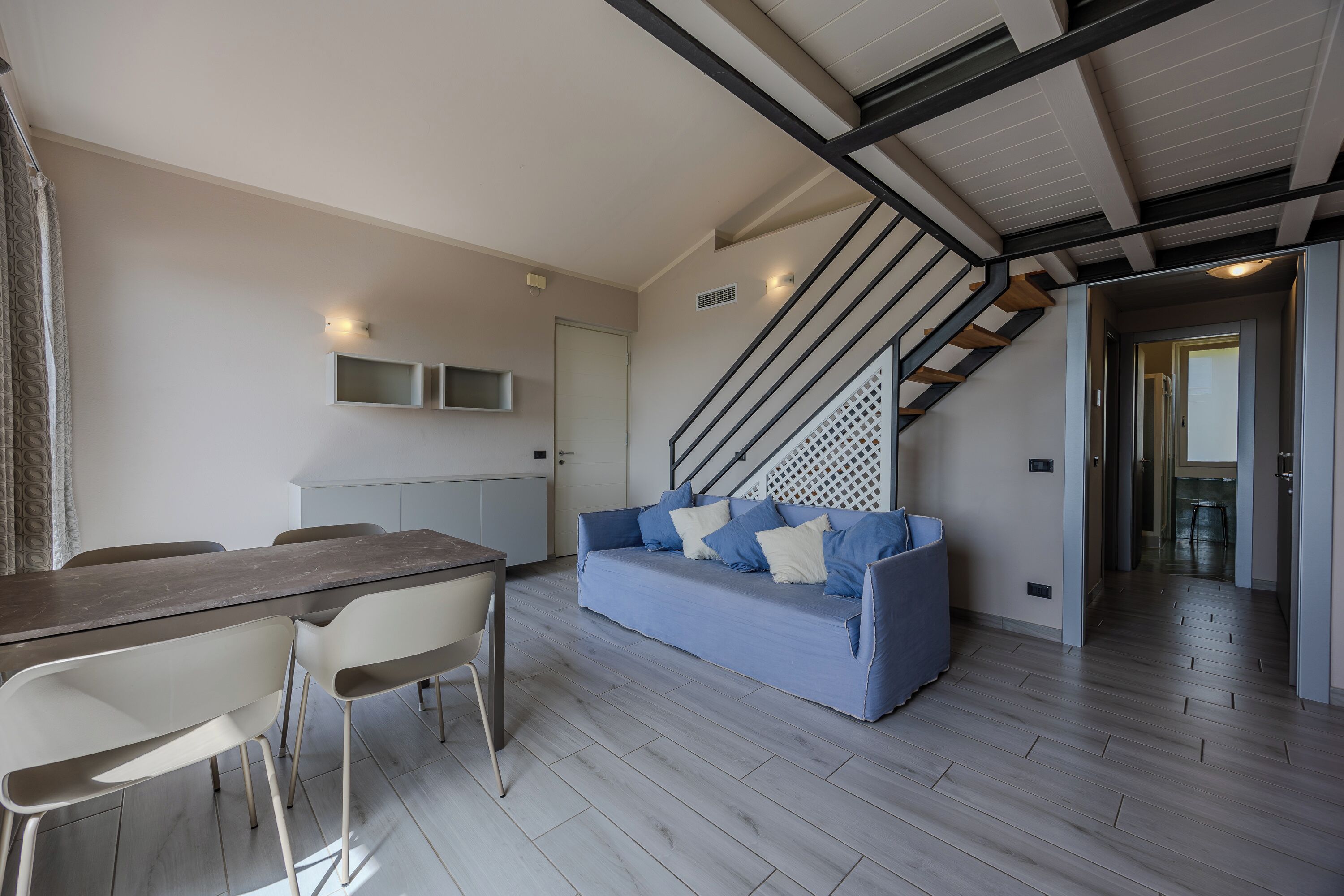 Una sala moderna con comedor, escalera y cocina.