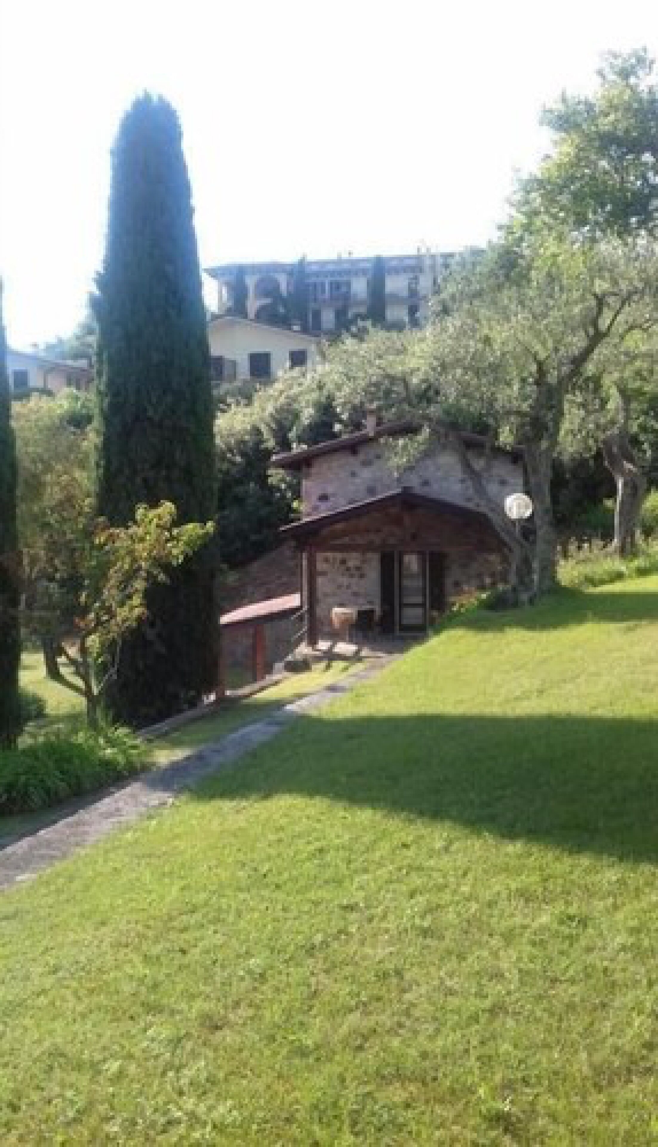 A rustic building with a stone facade, a small porch, and a pathway leading to it.