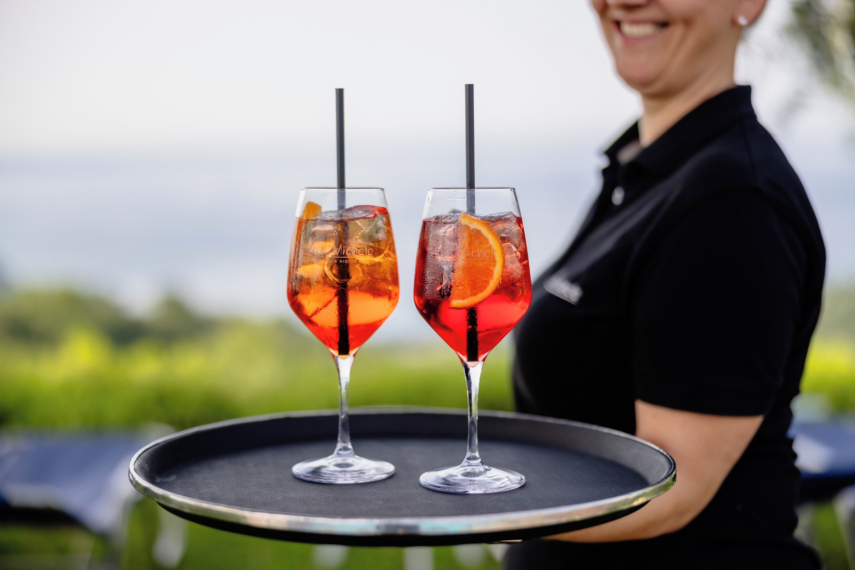Two glasses of red beverage with ice and orange slices on a tray.