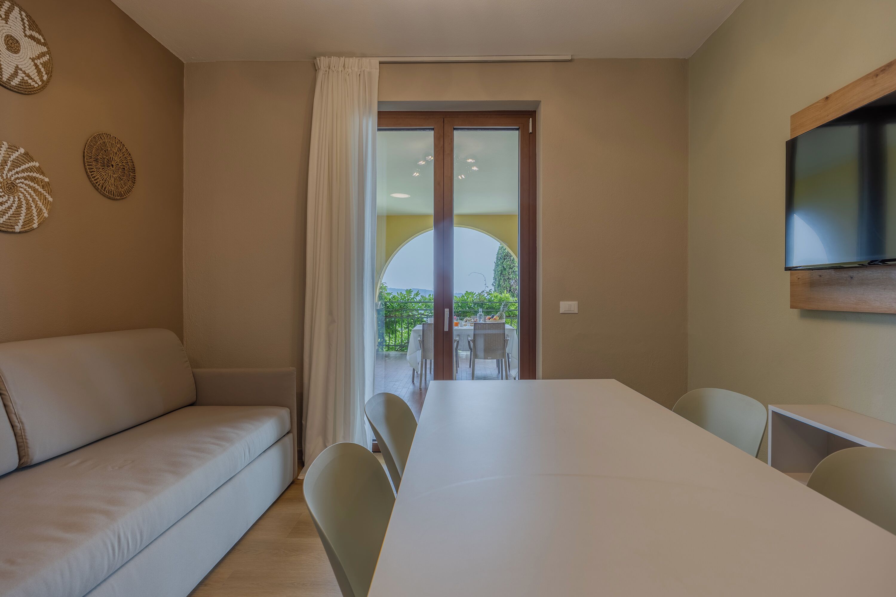 Une pièce moderne comprenant un canapé, une table à manger, des chaises et un téléviseur.