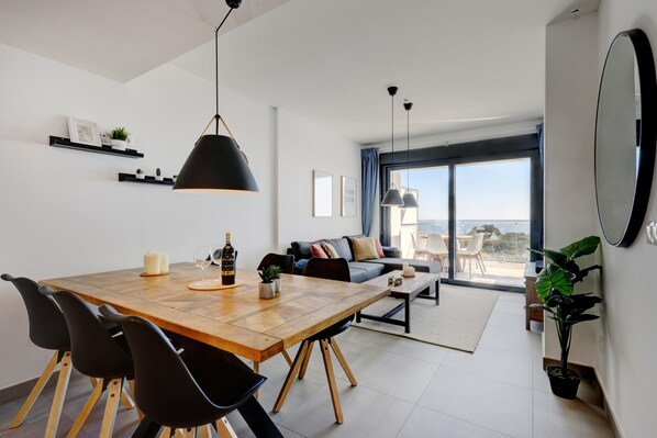 Un salon moderne comprenant un coin repas, un canapé et une grande fenêtre.
