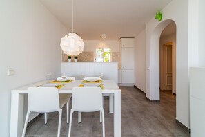 Un espace repas avec une table blanche, des chaises et un grand luminaire en forme de fleur.