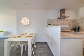 Une cuisine moderne avec des meubles blancs, un pare-feu en pierre et un luminaire suspendu au-dessus de la table à manger.