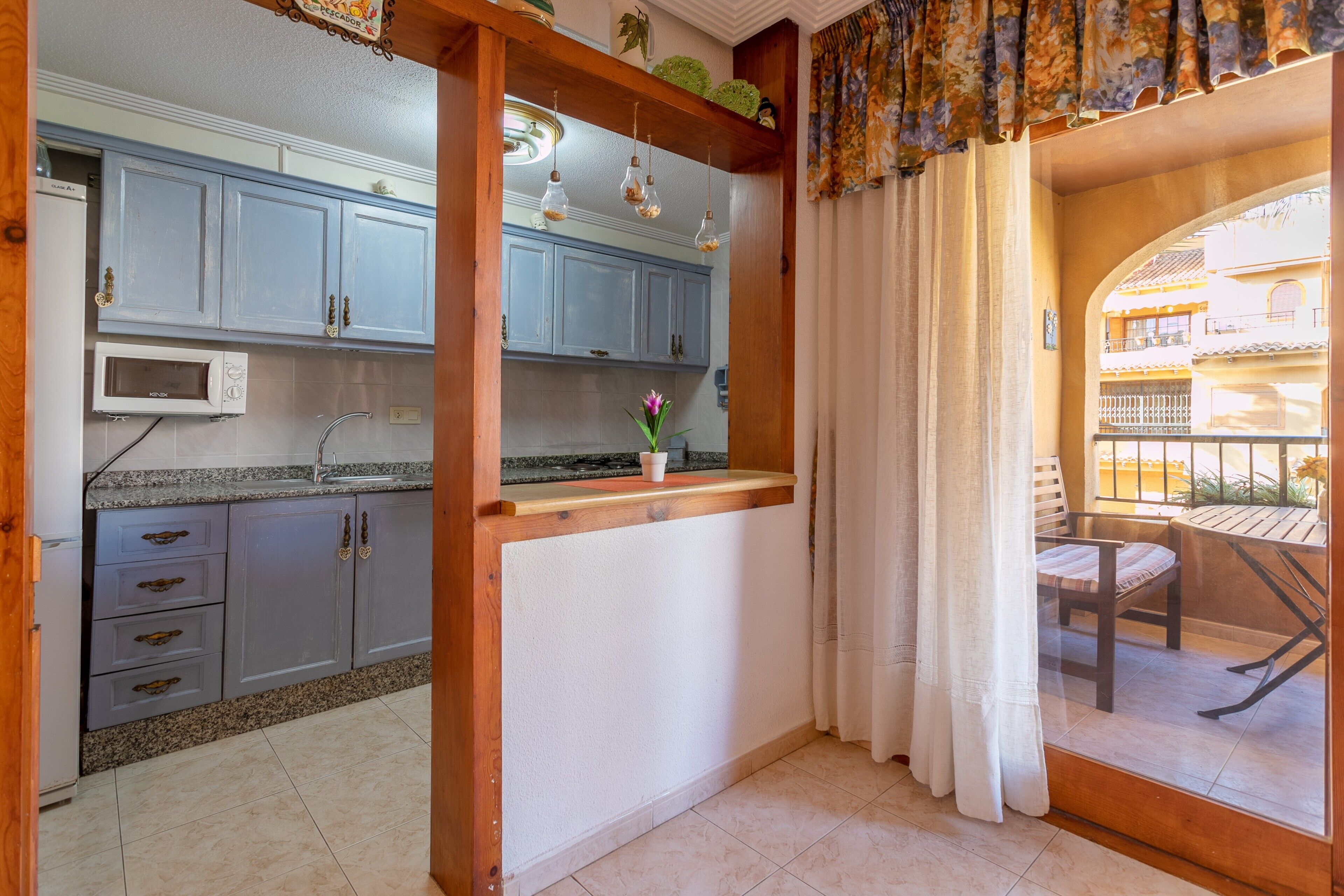 Una cocina con gabinetes grises, un microondas y una pequeña encimera con un florero.
