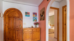 A hallway with a wooden door, a cabinet, and a bed in the background. - Apartment "El Albero" with Pool, Terrace & Wi-Fi (La Mata Torrevieja Alicante)