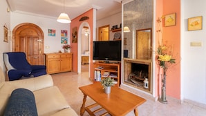 A living room with a sofa, a television, a fireplace, and a bookshelf. - Apartment "El Albero" with Pool, Terrace & Wi-Fi (La Mata Torrevieja Alicante)