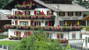 A multi-story building with balconies adorned with flowers, a sign reading 'RESIDENCE PICHLER,' and a ski slope visible in the background. - Apartment 'Residence Pichler 2' with Mountain View, Balcony & Wi-Fi (San Leonardo In Passiria)