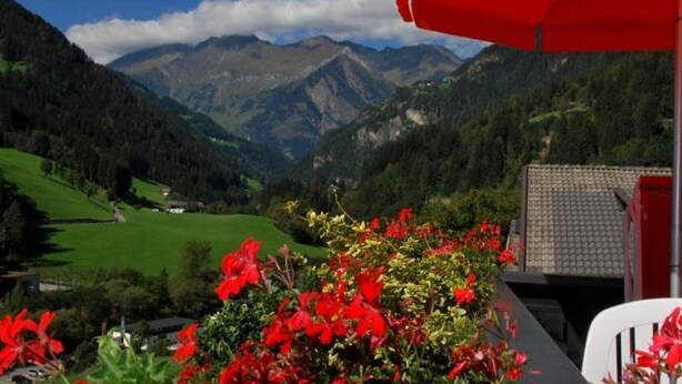 A mountain landscape with a red umbrella and flowers in the foreground. - Apartment 'Residence Pichler 2' with Mountain View, Balcony & Wi-Fi (San Leonardo In Passiria)