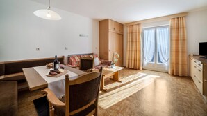 A modern living room with a sofa, dining table, and a television. - Apartment 'Residence Pichler 2' with Mountain View, Balcony & Wi-Fi (San Leonardo In Passiria)