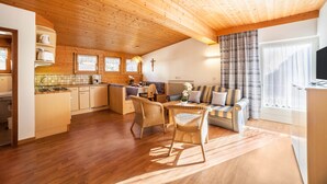 Interior acogedor de una cabaña con techo de madera, zona de comedor, sofá y cocina.