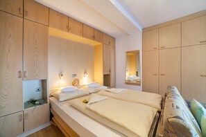 A bedroom with a large bed, wooden wardrobe, and a mirror.