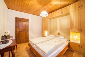 Una habitación con paneles de madera, dos camas, una puerta de madera y una mesa con un florero.