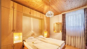 Une pièce aux murs lambrés, avec un lit, des lampes de chevet et un miroir.