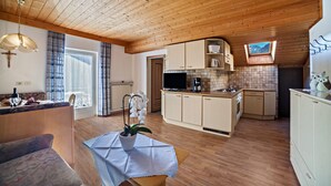 Eine gemütliche Küche mit Holzschränken, einem Essbereich mit Tisch und Stühlen sowie einem kleinen Fenster.