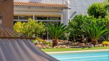 A pool area with a clear view of a building with large windows and a tiled roof.