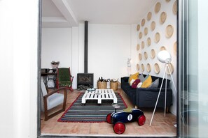 A living room with a sofa, a coffee table, a rocking chair, a fireplace, and a wall decorated with circular patterns.