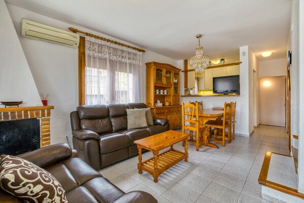 A living room with a sofa, a wooden table, and a TV. - Holiday Home "Ampuriabrava" with Wi-Fi & A/C (Castello d'Empuries)