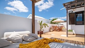 A modern outdoor living area with a sofa, a yellow blanket, a dining table, and chairs. - Villa 'Princesa Faina' with Partial Sea Views, Private Pool and Wi-Fi (Tias)