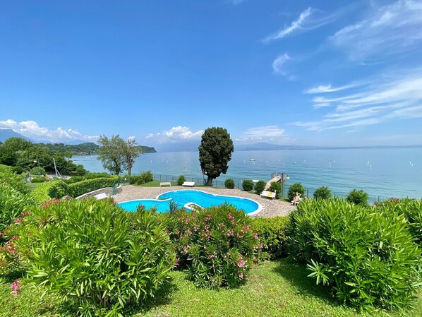 Una piscina circondata da rigogliosa vegetazione e una vista limpida sul lago.
