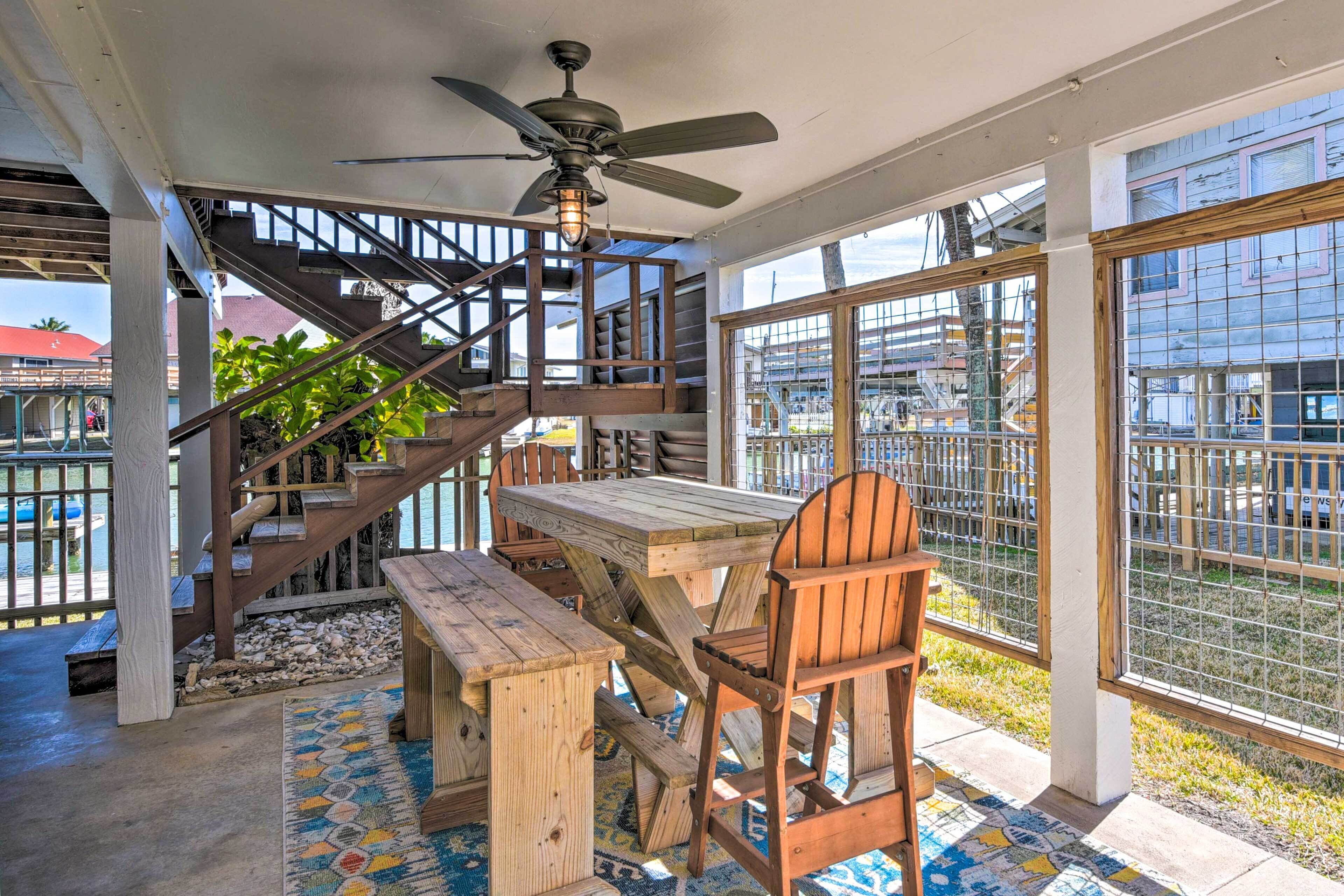 A wooden dining area with a table and benches, a ceiling fan, and a staircase leading to an upper level.
