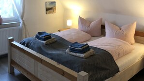 Ett sovrum med en säng, ett nattduksbord, en lampa och ett fönster med gardiner.