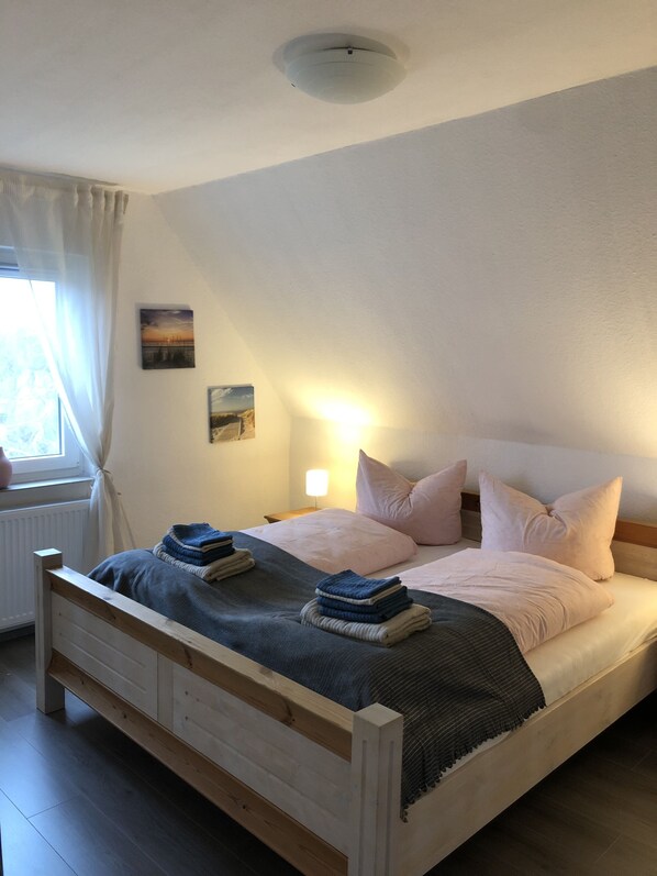 A bedroom with a bed, a nightstand, a lamp, and a window with curtains.