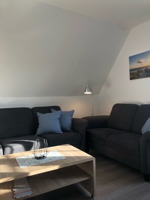A modern living room with a dark-colored sofa, a wooden coffee table, and a floor lamp.