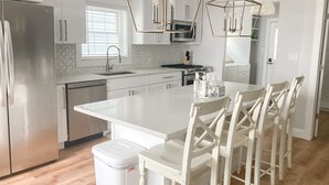 Une cuisine moderne dotée d’un îlot central, d’appareils électroménagers en acier inoxydable et de meubles blancs.