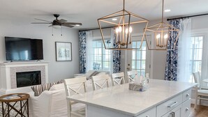 Une cuisine moderne dotée d’un îlot central, de meubles blancs et d’un ventilateur de plafond.
