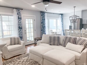 A modern living room with a sofa set, a dining area, and a kitchen.