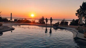 A pool area with a sunset view, lounge chairs, and a railing. - Il corbezzolo Tropea residence (Ricadi)