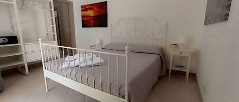 A bedroom with a bed, a wardrobe, a nightstand, and a painting on the wall.