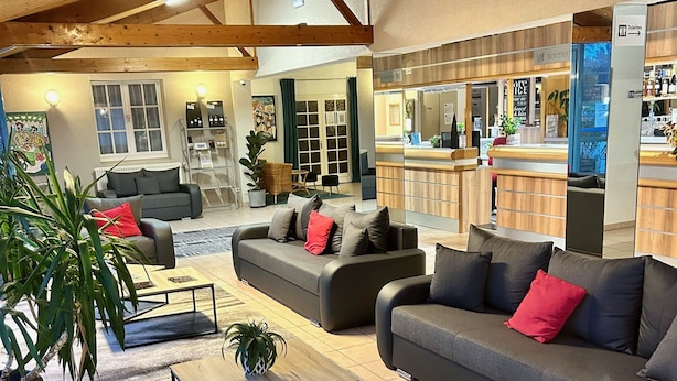 A spacious living area with a high ceiling, a seating arrangement including sofas and armchairs, a coffee table, and a potted plant. - Le Mas des Marais (Machecoul-Saint-Même)