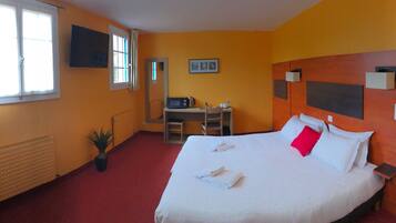 Habitación de hotel con cama, escritorio, televisor y radiador.