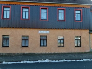 A building with a dark facade and red-framed windows, featuring a sign that reads "Das alte E-Werk".