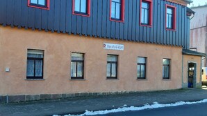 Rakennuksessa on tummansininen julkisivu ja punaiset ikkunakarit, ja sen yläpuolella on kyltti, jossa lukee: ”Das alte E-Werk”.