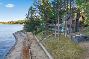 A lakeside property with a multi-level house, a dock, and a pathway leading to the water.