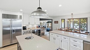 A modern kitchen with stainless steel appliances, a large island, and a dining area with natural light.