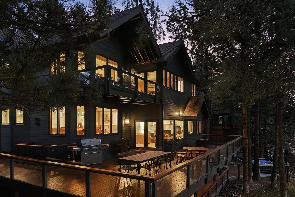 A multi-level wooden cabin with a deck, large windows, and a fireplace.