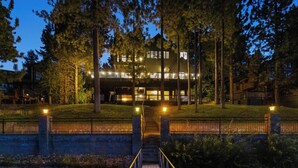 A modern building with multiple levels, surrounded by trees and a well-lit pathway leading to the entrance.