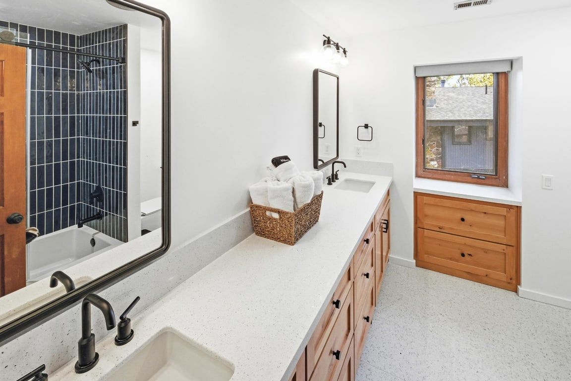 Un baño con lavamanos doble, espejo, tocador de madera y ventana.