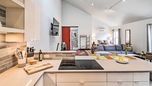 A modern kitchen with a central island, built-in appliances, and a dining area with a sofa and coffee table. - Contemporary-Boho Loft in Downtown Livingston! (Livingston)