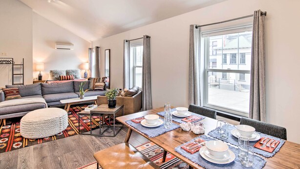 A modern living room with a sofa, coffee table, and dining area set for a meal. - Contemporary-Boho Loft in Downtown Livingston! (Livingston)