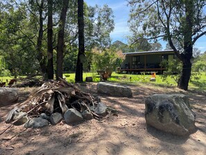 A rustic outdoor area with a pile of firewood and rocks, surrounded by trees.