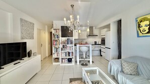 Ein modernes Wohnzimmer mit Fernseher, Bücherregalen, einer Chandelieber und einem Sofa.