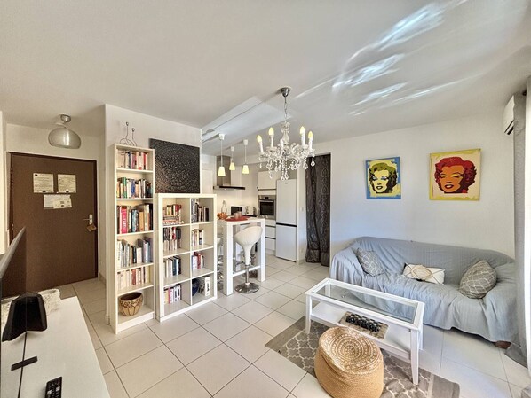 Uma sala de estar moderna com sofá, mesa de centro, estantes e um lustre.